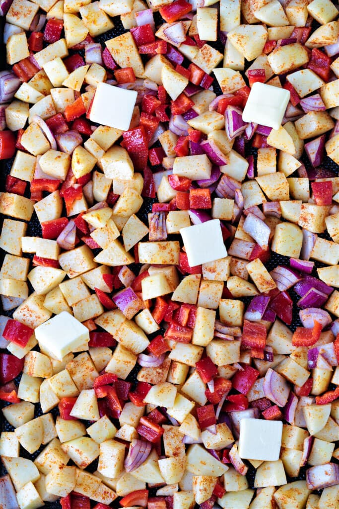 potatoes, peppers and onions on a sheet pan with butter