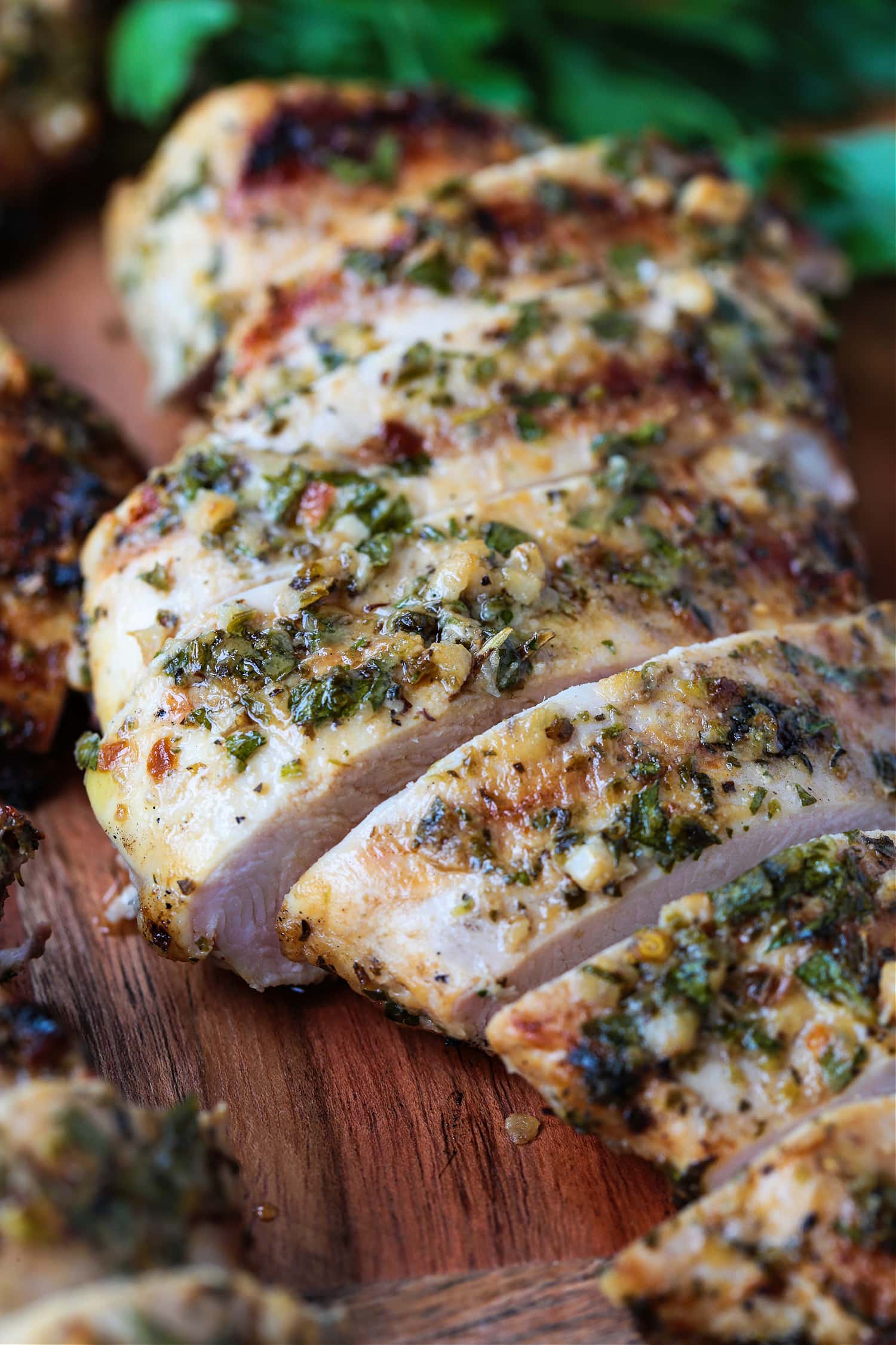 marinated chicken breast sliced on a board with parsley