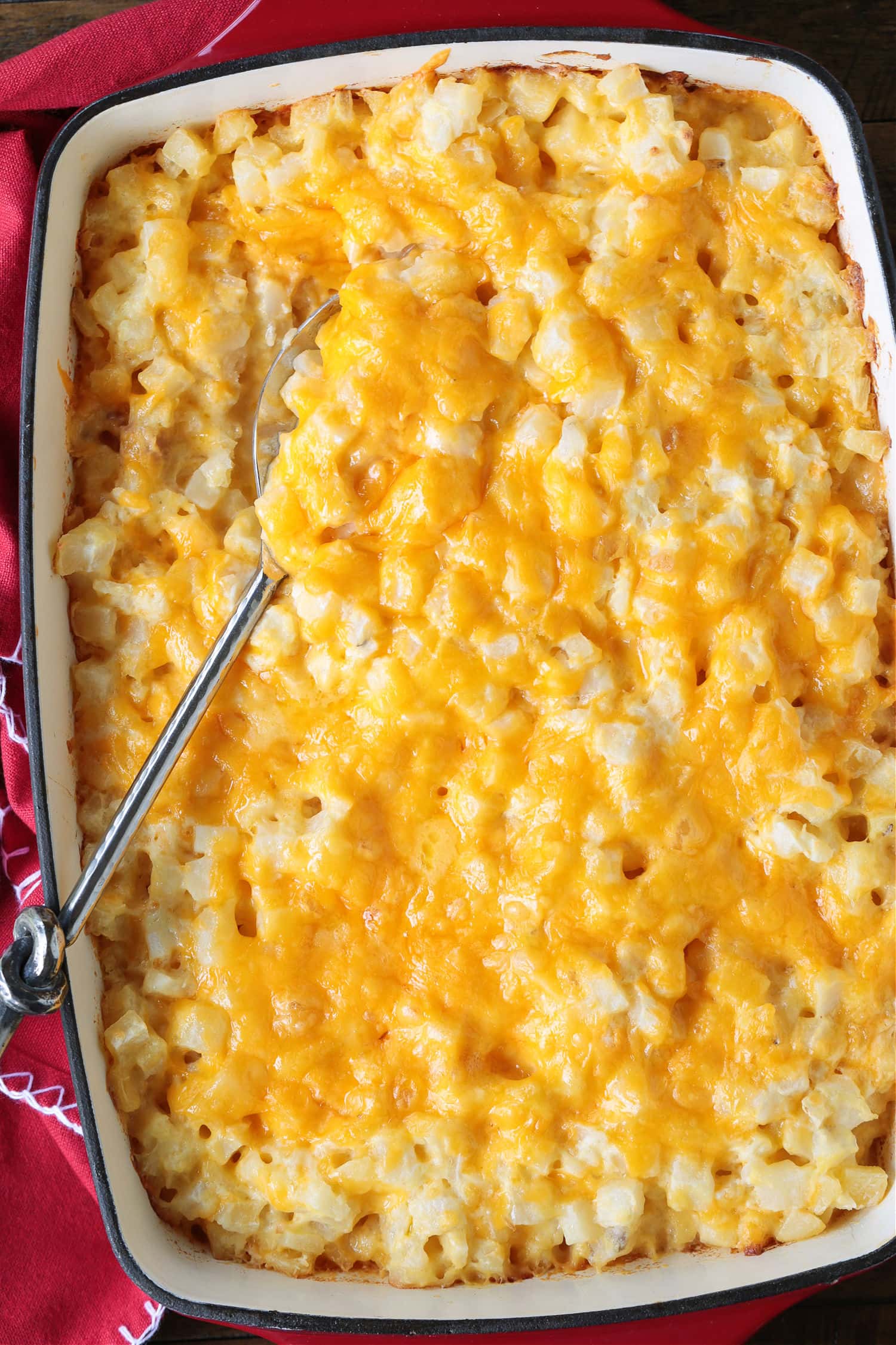 potato casserole topped with cheese and spoon on the side