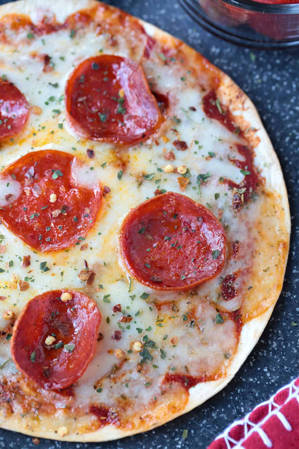 An Air Fryer Tortilla Pizza is perfect for an after school snack or an easy meal! A thin, crispy crust with gooey cheese ready in minutes! close up of air fryer tortilla pizza with pepperoni