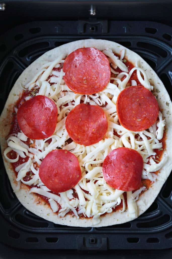 An Air Fryer Tortilla Pizza is perfect for an after school snack or an easy meal! A thin, crispy crust with gooey cheese ready in minutes! tortilla pizza with pepperoni in air fryer