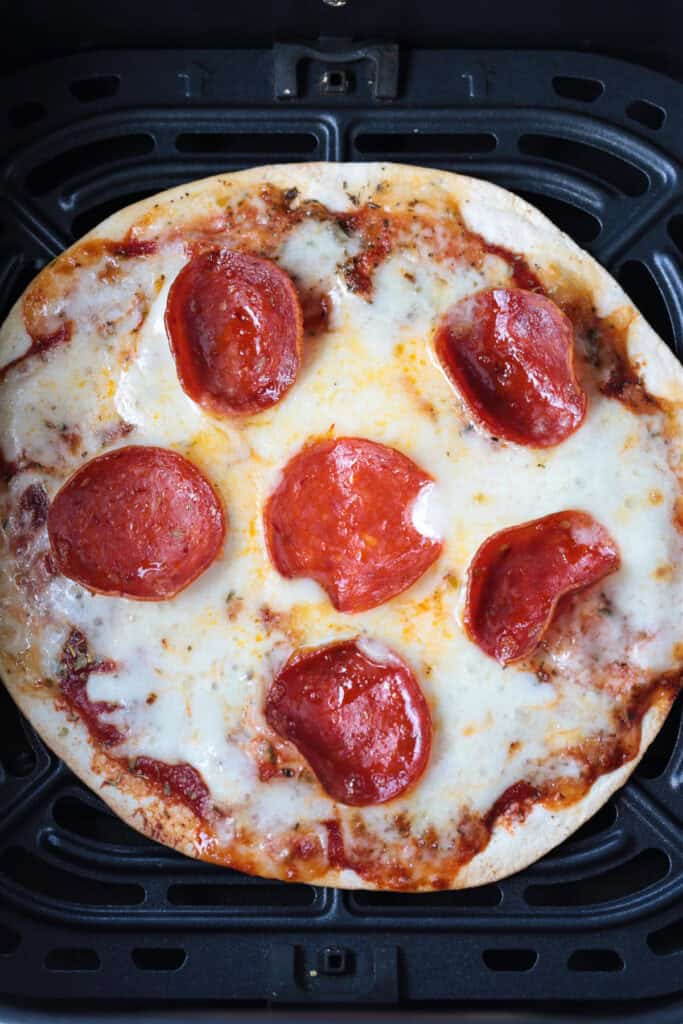 An Air Fryer Tortilla Pizza is perfect for an after school snack or an easy meal! A thin, crispy crust with gooey cheese ready in minutes! air fryer tortilla pizza cooked