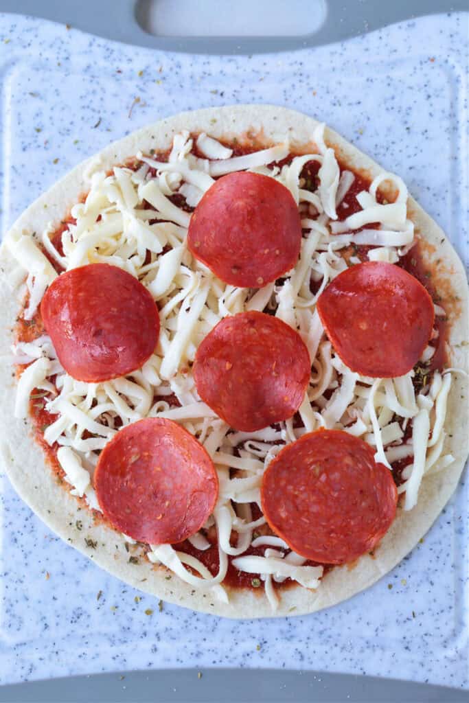 An Air Fryer Tortilla Pizza is perfect for an after school snack or an easy meal! A thin, crispy crust with gooey cheese ready in minutes! tortilla pizza with pepperoni on board