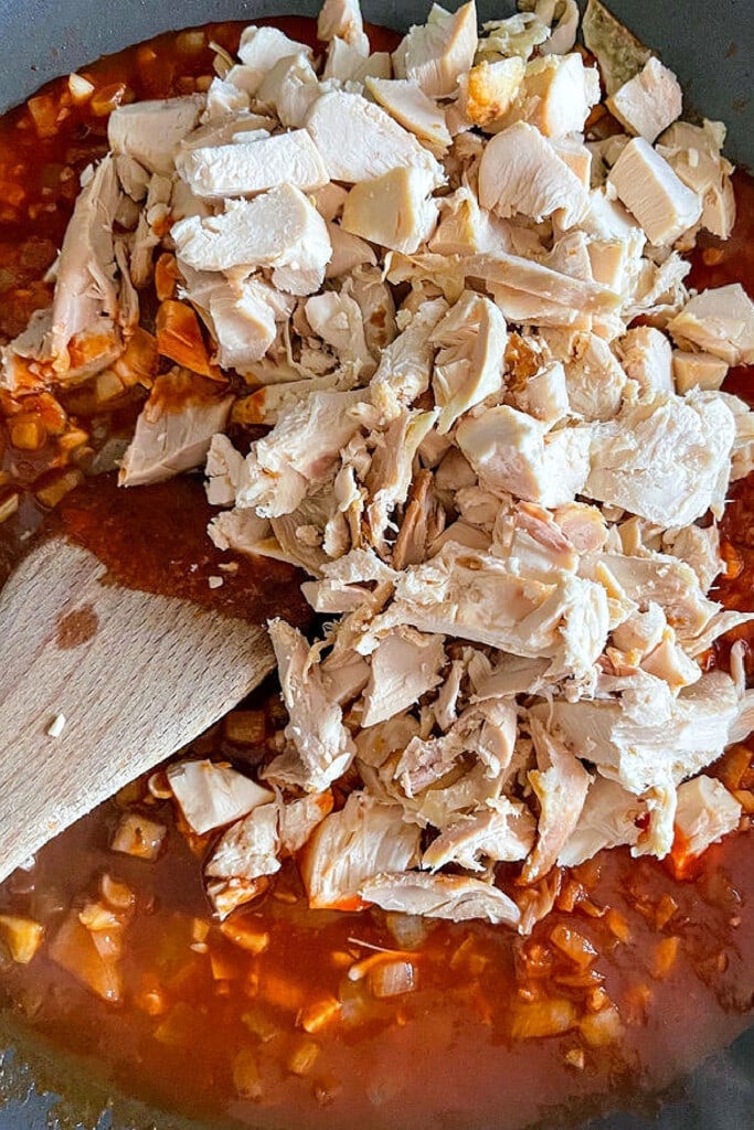 Chicken Chimichangas are super crispy and oozing with flavor! A chicken and cheese filling tucked inside a crispy, pan-fried tortilla. shredded chicken in skillet with sauce