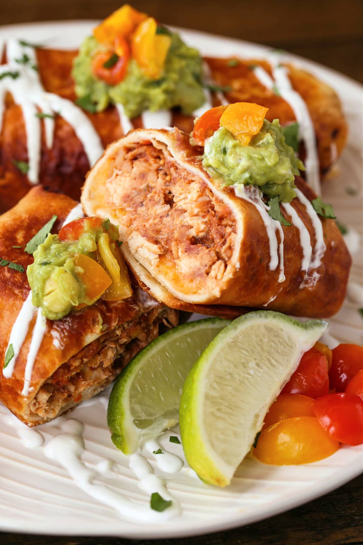 Chicken Chimichangas are super crispy and oozing with flavor! A chicken and cheese filling tucked inside a crispy, pan-fried tortilla. Chicken Chimichangas cut on a plate for serving