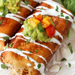 Chicken Chimichangas on a plate with sour cream drizzle