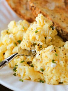 scrambled eggs on a plate with toast and a fork
