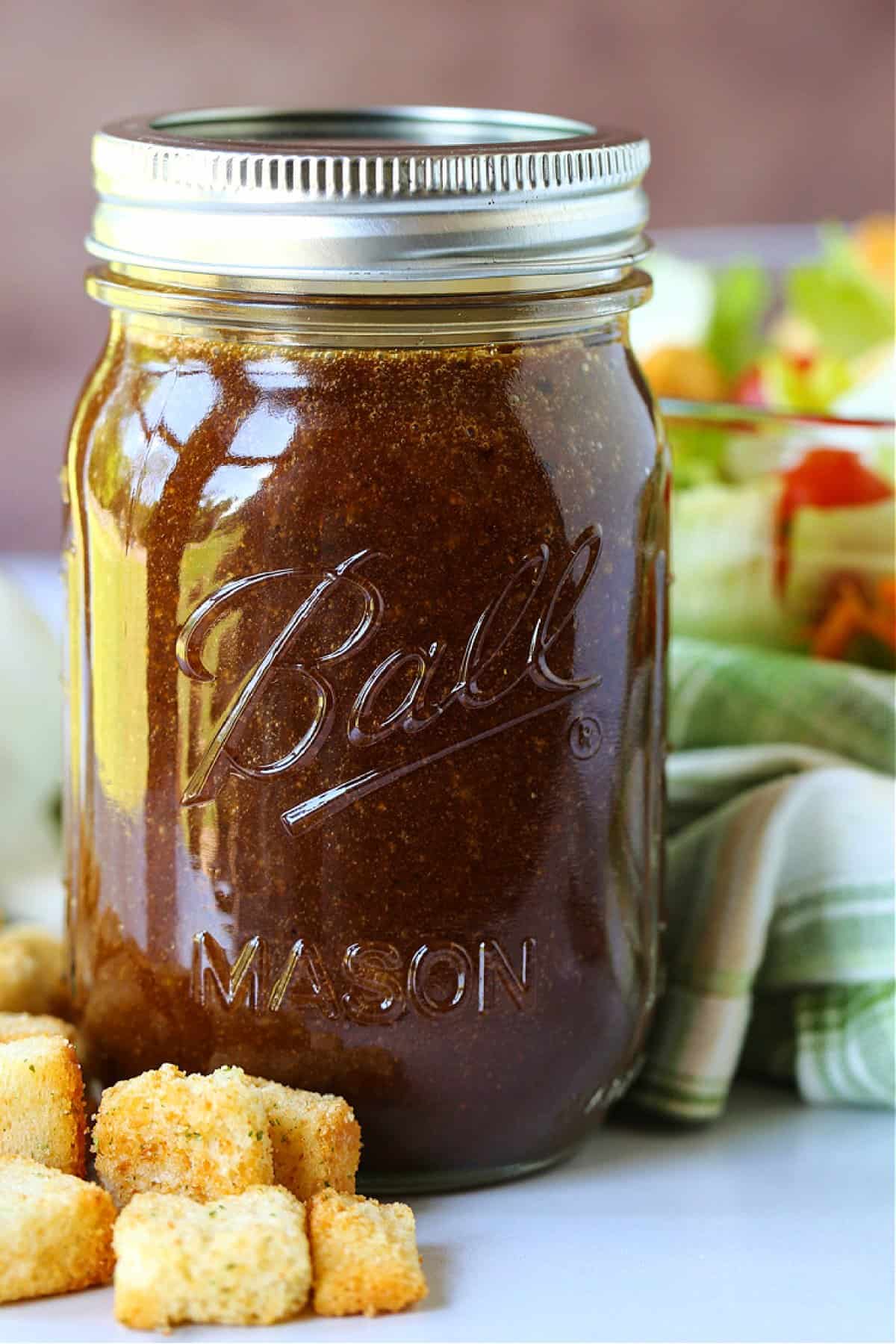 mason jar with balsamic dressing in front of salad bowl