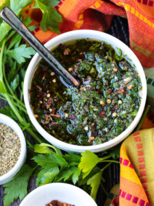 chimichurri sauce in bowl with spoon and colorful napkin