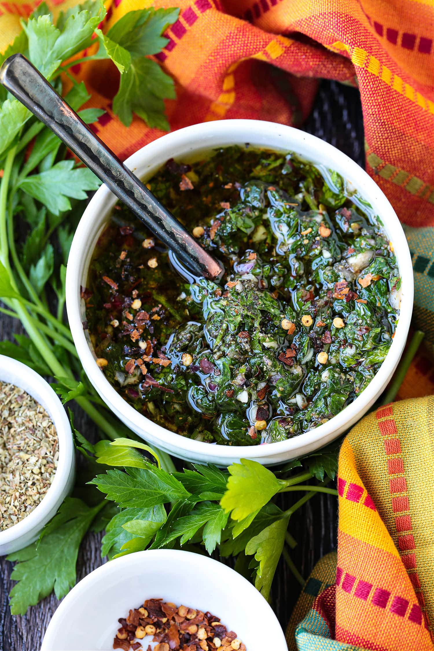 chimichurri sauce in bowl with spoon and colorful napkin