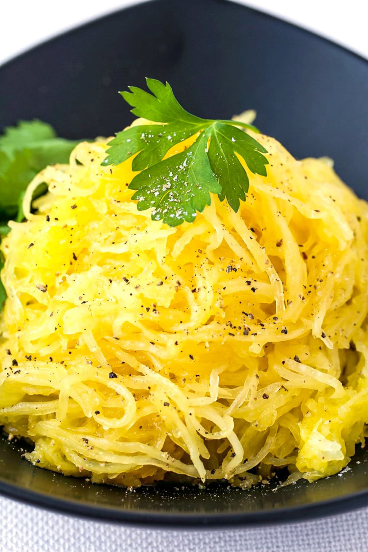 mound of spaghetti squash on black plate with parsley