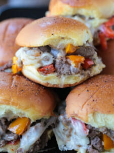 philly cheesesteak sliders stacked on plate