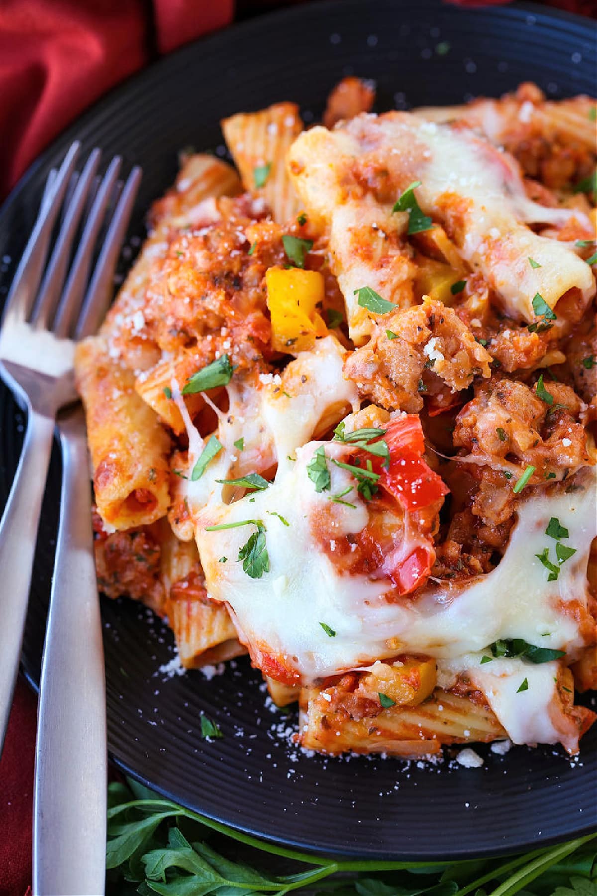 baked ziti on a black plate with forks