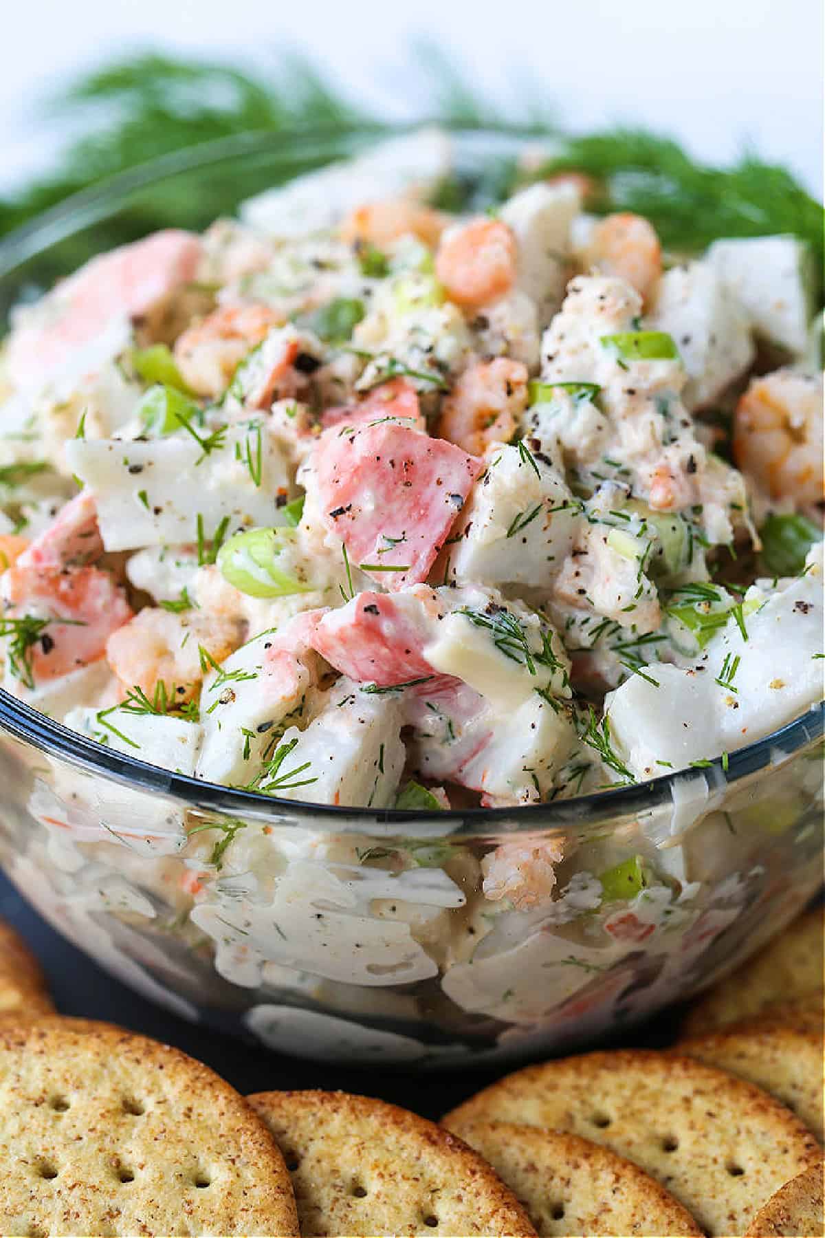 Creamy Seafood Salad is so delicious piled onto crackers or on a roll! An easy seafood appetizer that's perfect for parties and holidays! bowl of cold seafood salad with fresh dill garnish