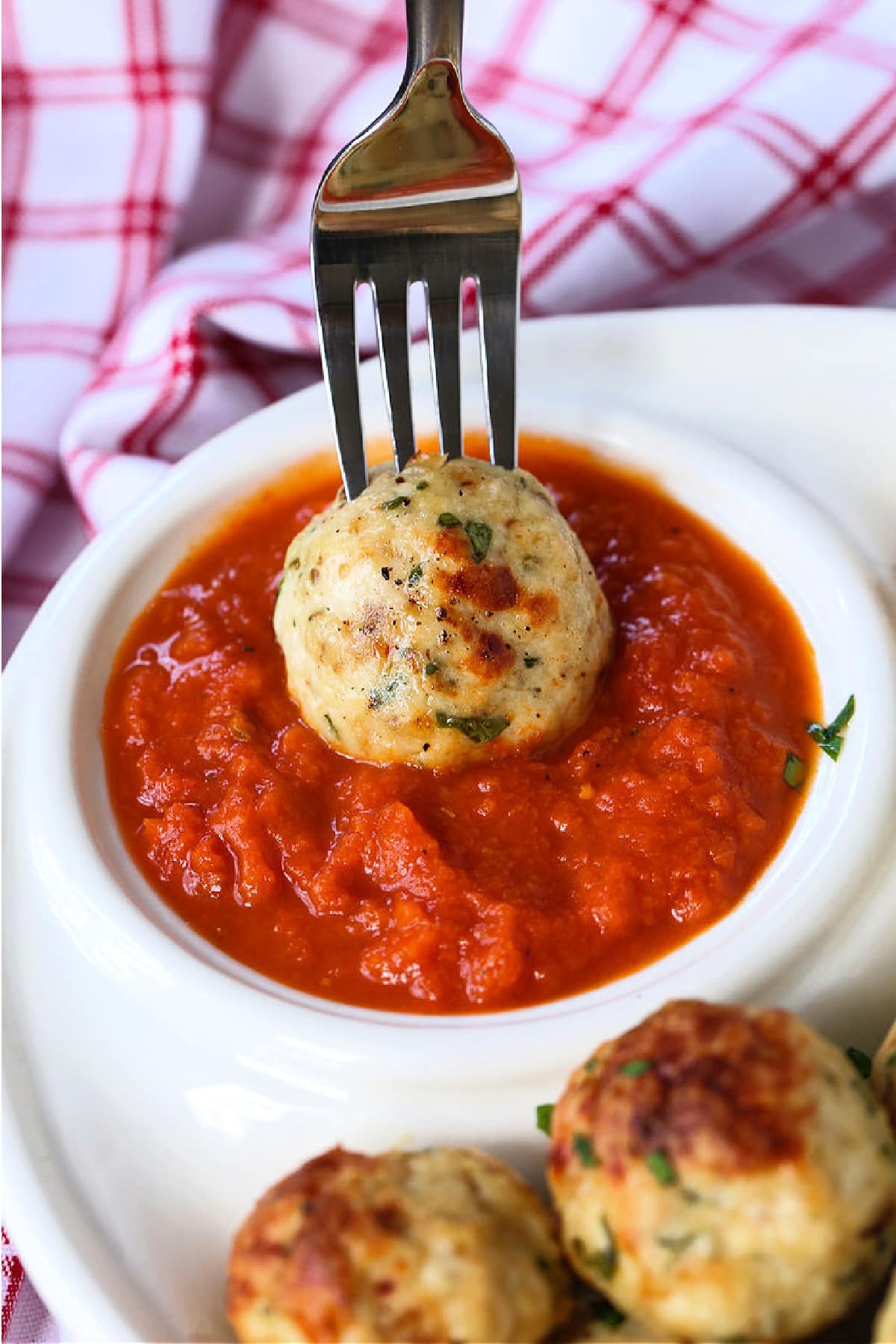 chicken meatball on a fork dipping into sauce