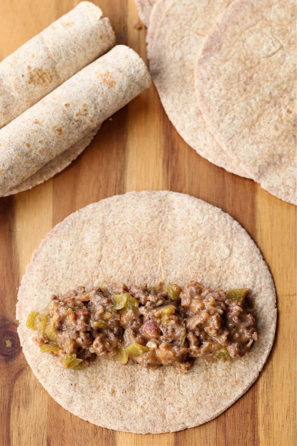 ground beef and cheese filling in a line across a tortilla