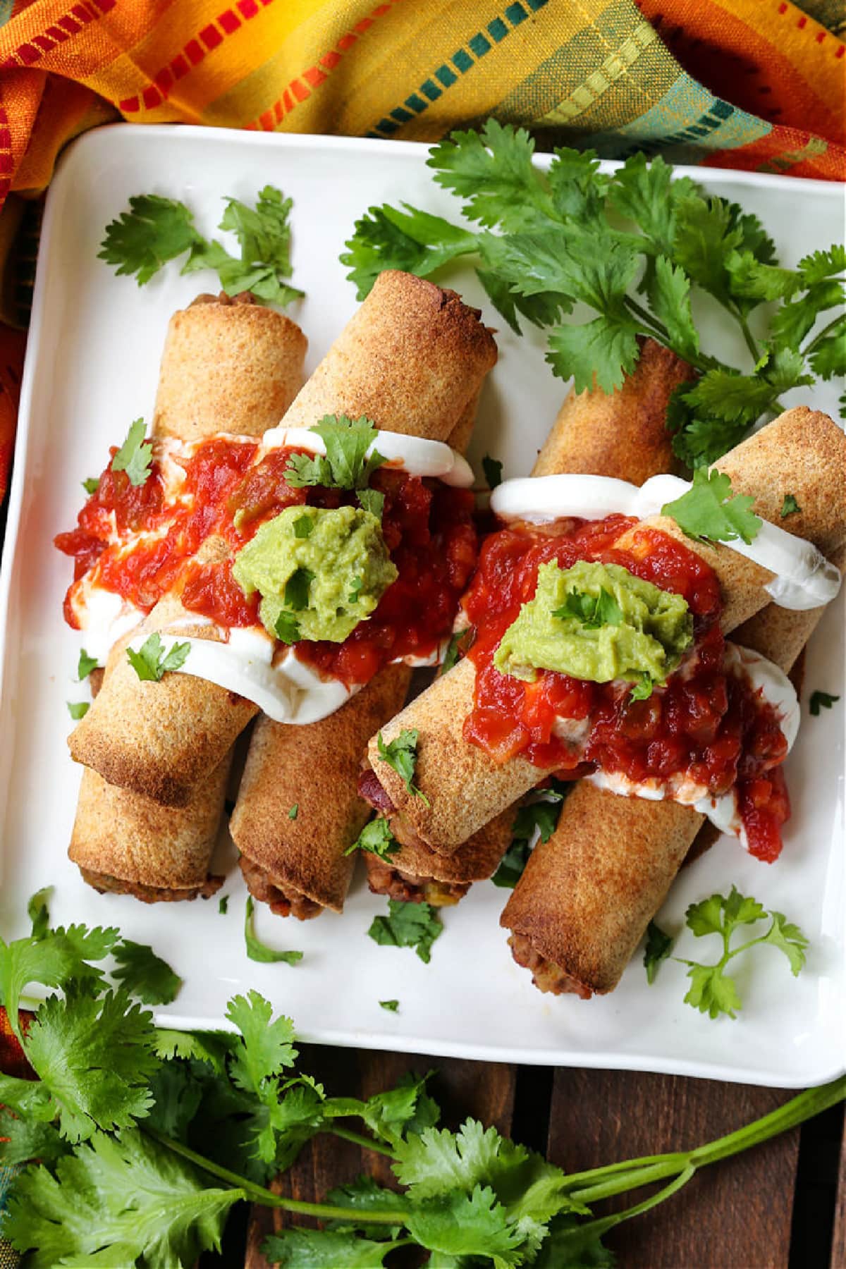 beef taquitos on a plate with salsa and guacamole