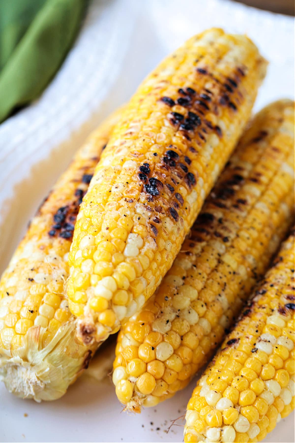 grilled corn on the cob on a white platter