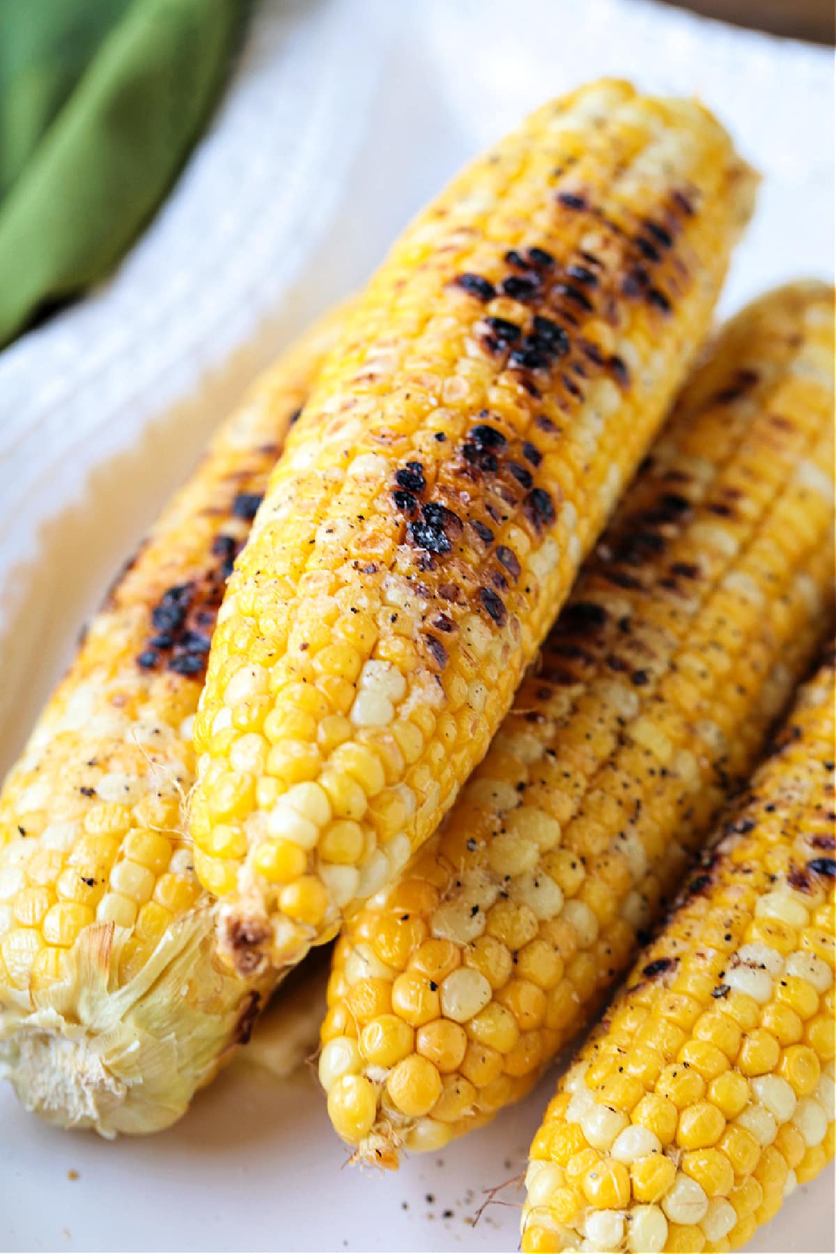 Corn on the Cob on the Grill is an easy and delicious way to make corn! Sweet corn with a charred flavor that makes the perfect summer side! grilled corn on the cob on a white platter