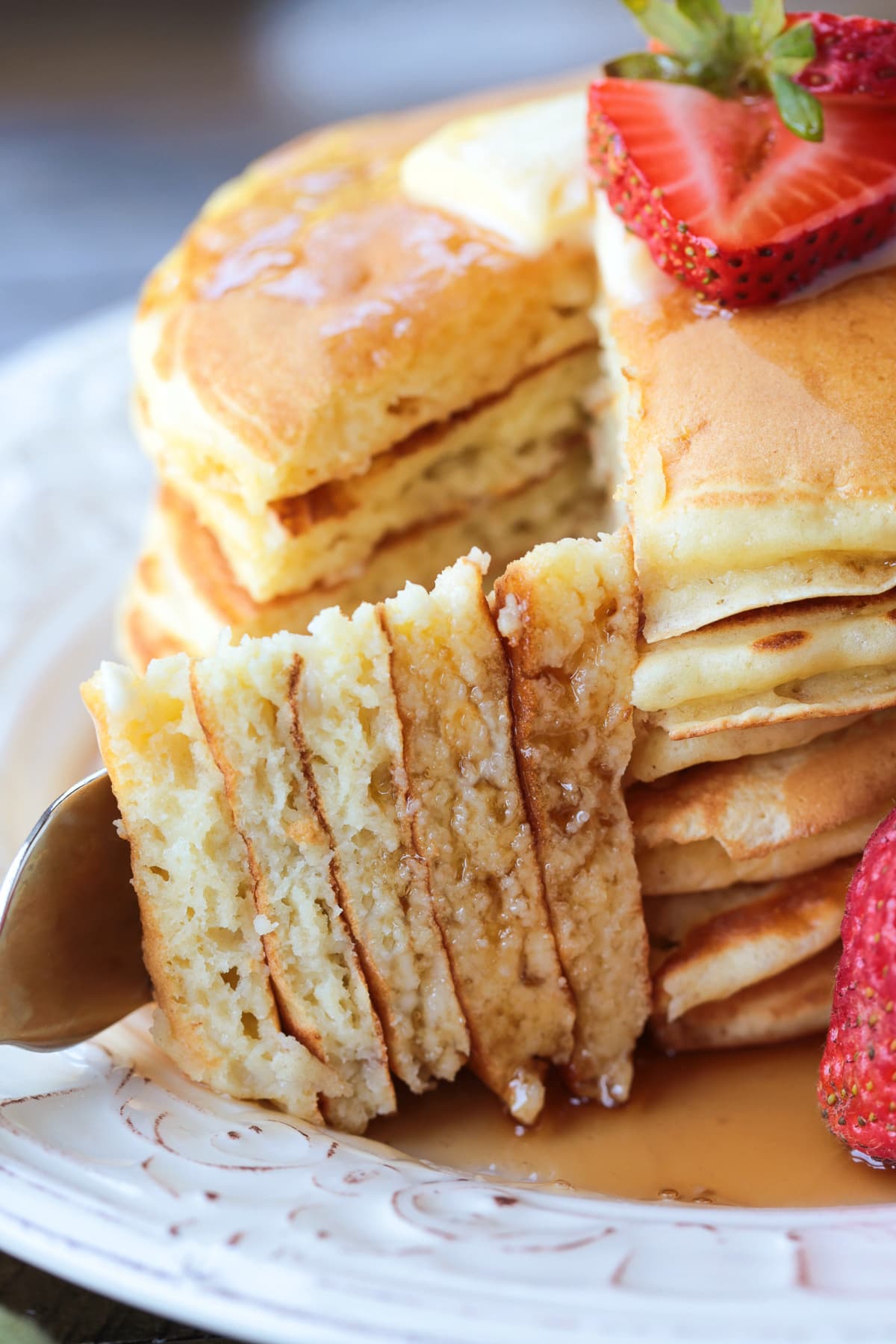 a fork holding a wedge of pancakes with pancake stack in background