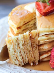 a fork holding a wedge of pancakes with pancake stack in background