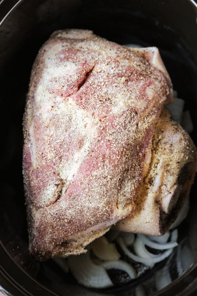 seasoned pork should in a slow cooker on top of onions