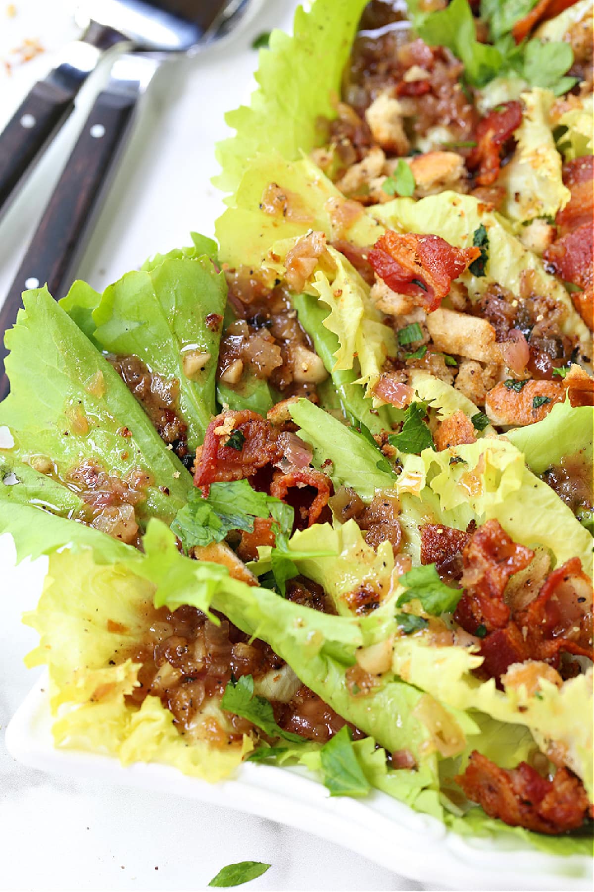 This Escarole Salad Recipe always gets rave reviews! Slightly bitter greens tossed with buttery croutons and a warm bacon dressing. escarole salad shown close up from the corner of a platter
