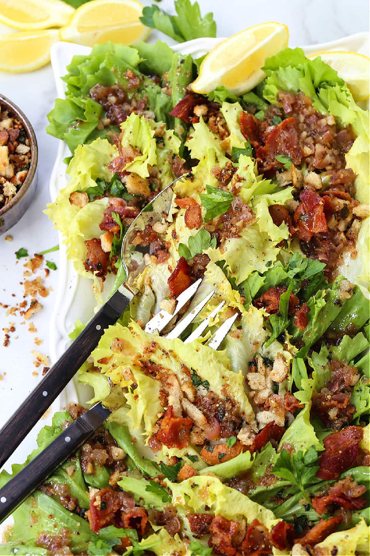 This Escarole Salad Recipe always gets rave reviews! Slightly bitter greens tossed with buttery croutons and a warm bacon dressing. escarole salad with bacon and breadcrumbs on platter