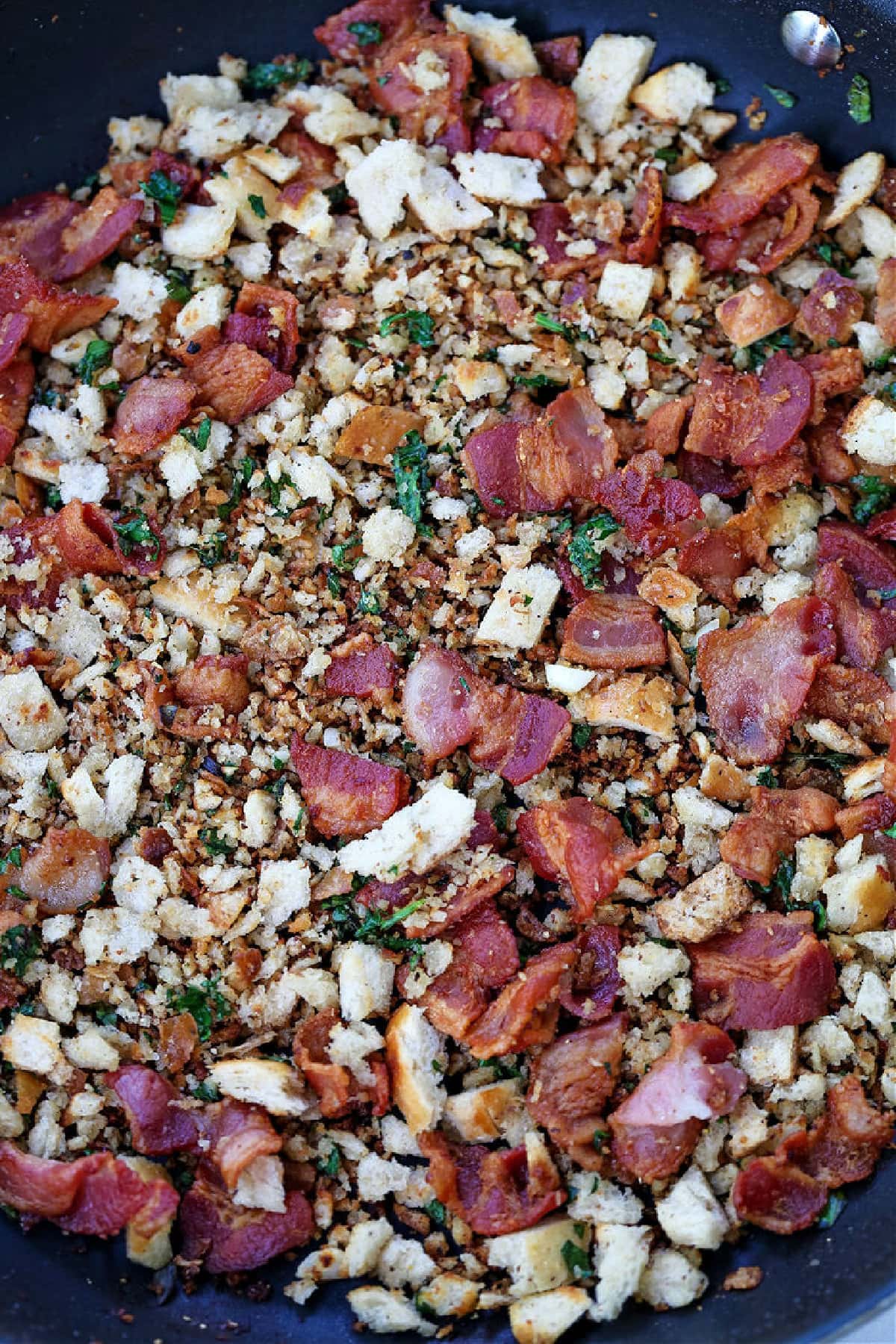 This Escarole Salad Recipe always gets rave reviews! Slightly bitter greens tossed with buttery croutons and a warm bacon dressing. bacon and breadcrumbs in a skillet