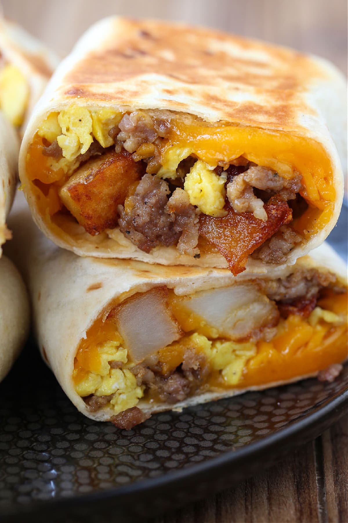 Breakfast Burritos with cheese, sausage, potatoes and egg cut in half on a plate