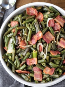 green beans with bacon and onions in a bowl with spoon