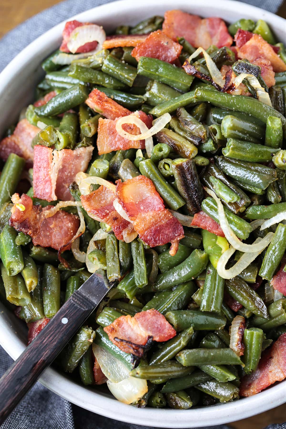 green beans with bacon and onions in bowl with spoon