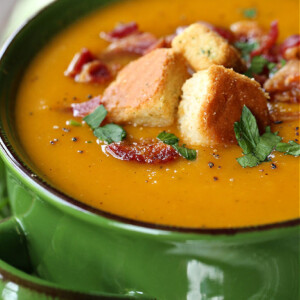 butternut squash soup in a green bowl with croutons and bacon
