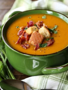 butternut squash soup in green crock with napkin and spoon on the side