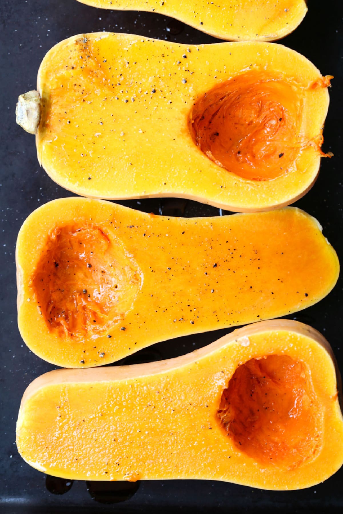 Filled with warm autumn spices, this smooth and creamy Roasted Butternut Squash Soup is the perfect comfort food to curl up with this fall. butternut squash halves on a baking sheet with salt and pepper