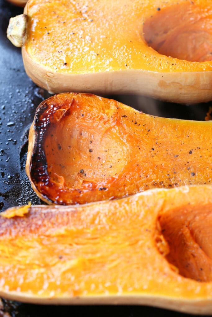 Filled with warm autumn spices, this smooth and creamy Roasted Butternut Squash Soup is the perfect comfort food to curl up with this fall. roasted butternut squash halves on a baking sheet