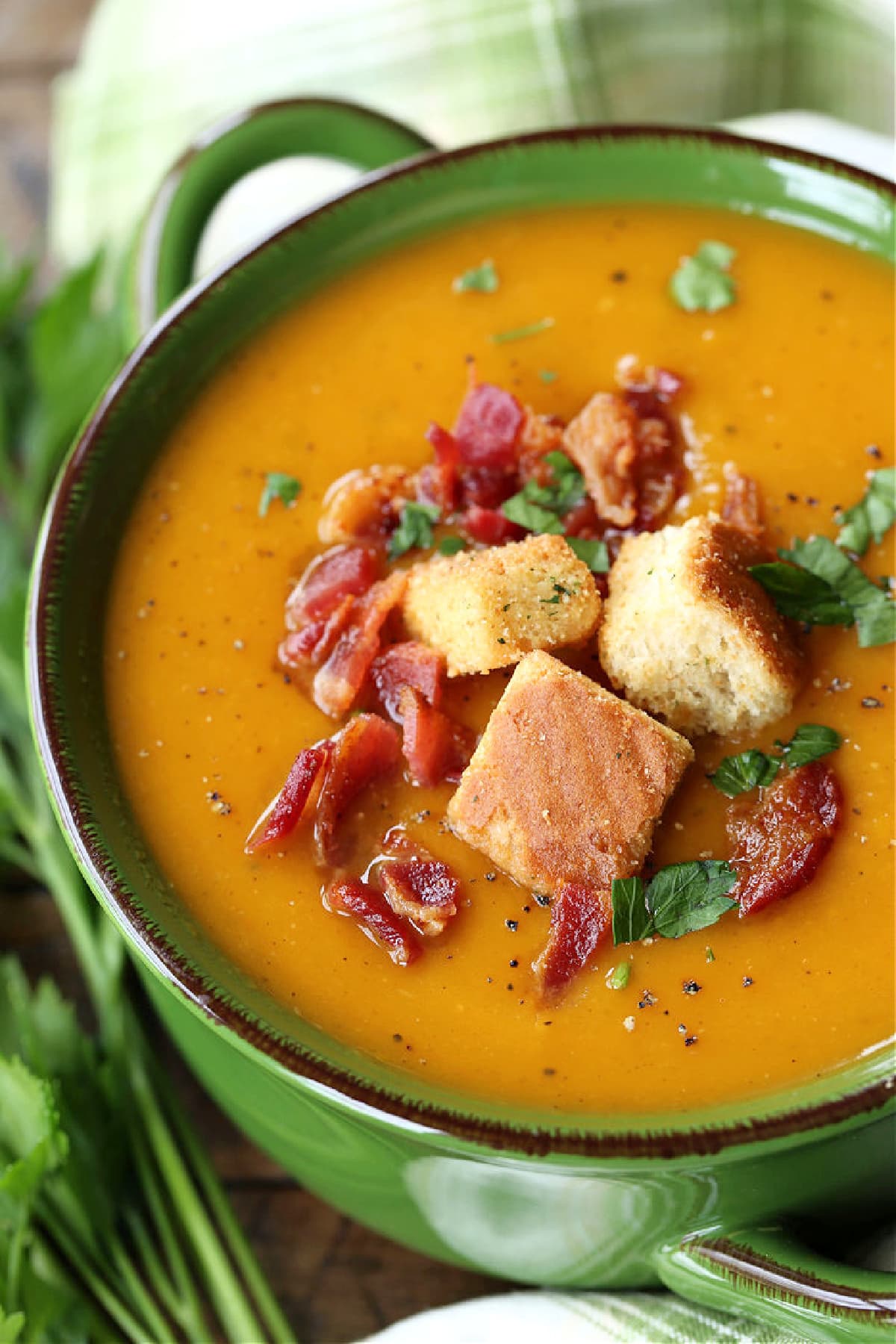 Roasted Butternut Squash Soup in a pot topped with bacon, parsley and croutons.