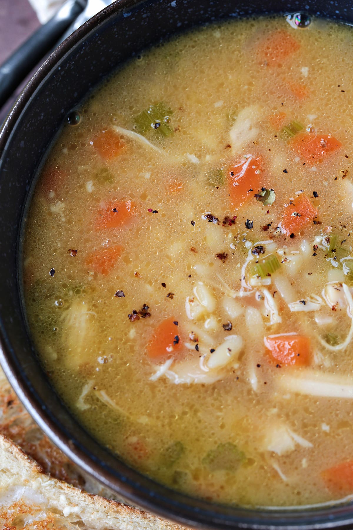 chicken soup in a bowl with toast on the side