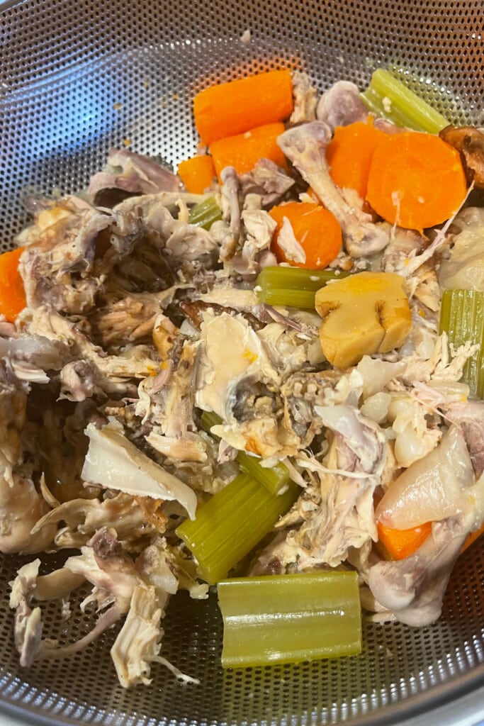Rotisserie Chicken Stock is so easy to make with leftover rotisserie chicken bones! Use this hearty chicken stock in soups, stews and more! strained chicken bones and vegetables from making stock