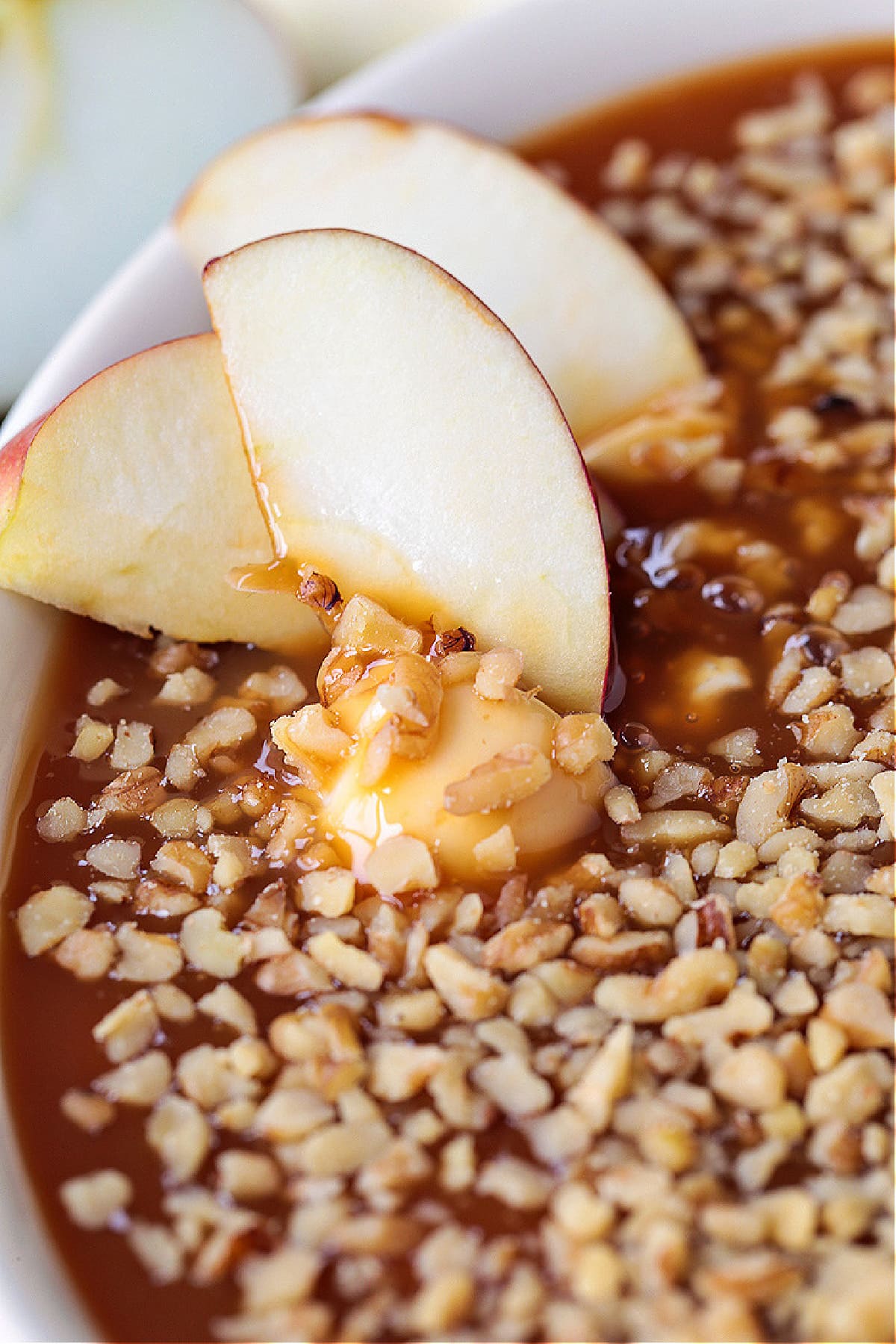 This Caramel Apple Dip is perfect for parties! An easy dessert recipe with the flavors of a nutty caramel apple and sweetened cream cheese. apple slices dipped in caramel apple dip