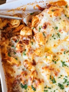 serving spoon in a casserole dish with tortellini and cheese