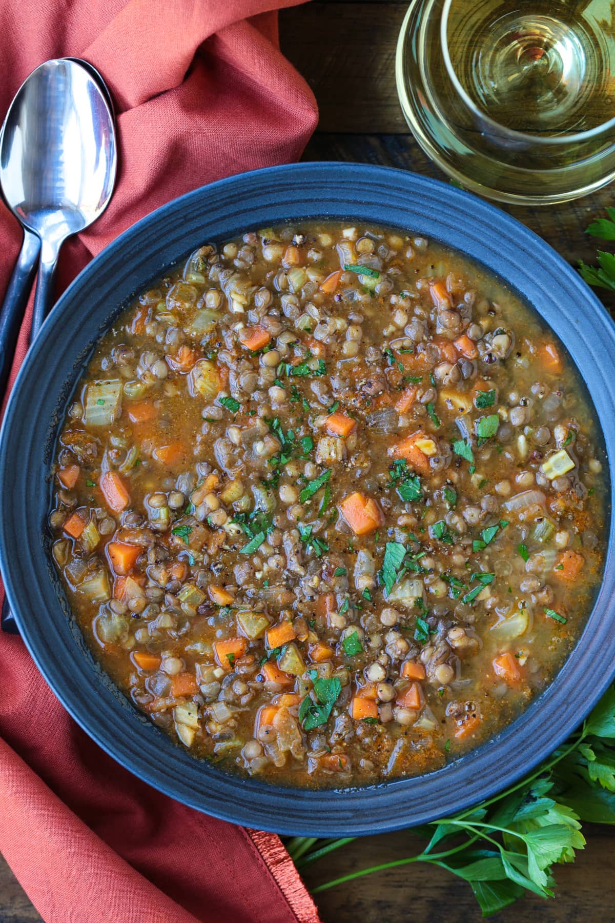 lentil soup in black bowl with napkin and spoons