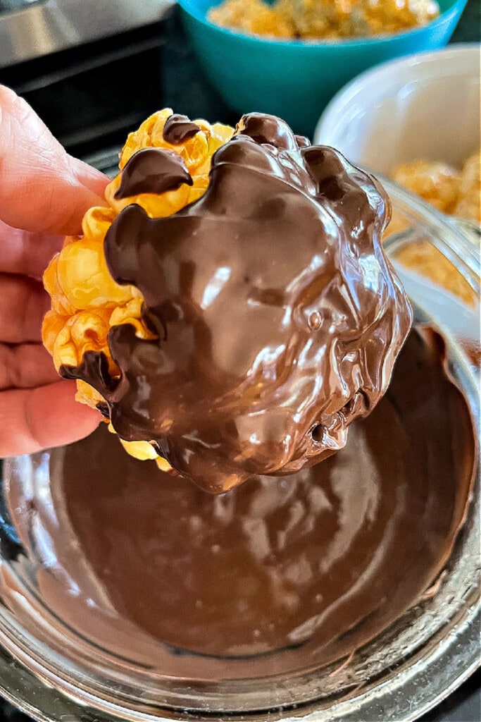 Halloween Popcorn Balls are a tasty and festive homemade treat for Halloween! Perfect for trick-or-treaters or for a Halloween party favor! Popcorn ball dipped in chocolate
