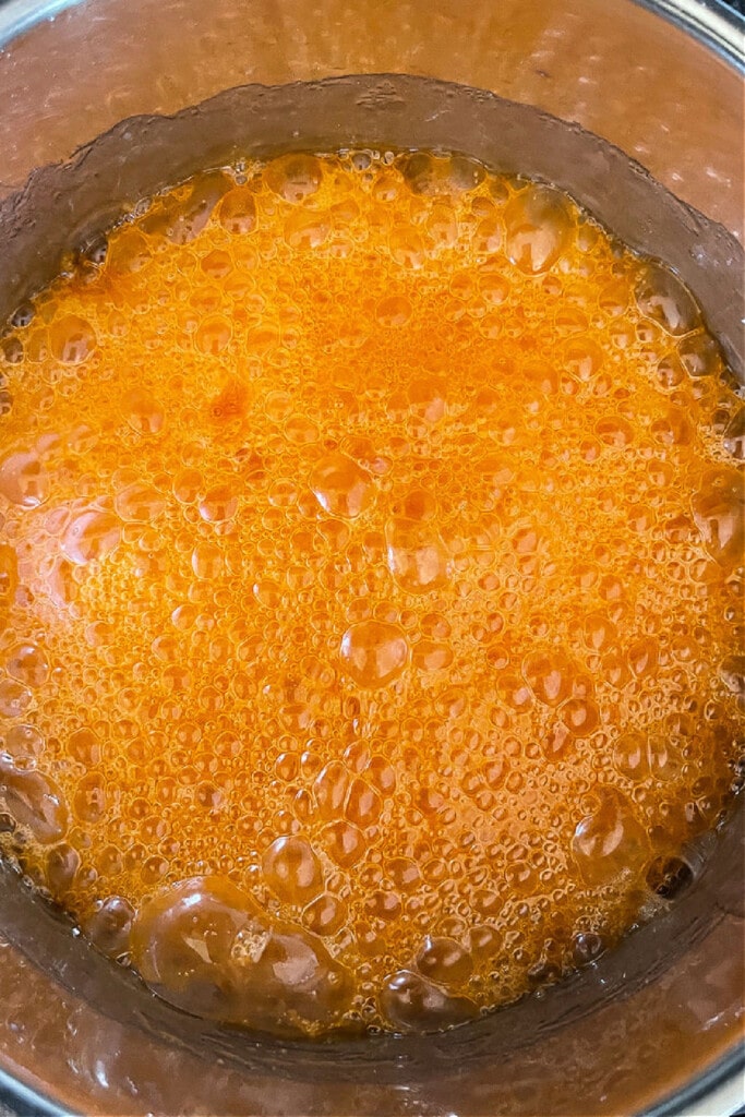 Halloween Popcorn Balls are a tasty and festive homemade treat for Halloween! Perfect for trick-or-treaters or for a Halloween party favor! orange colored corn syrup for popcorn balls