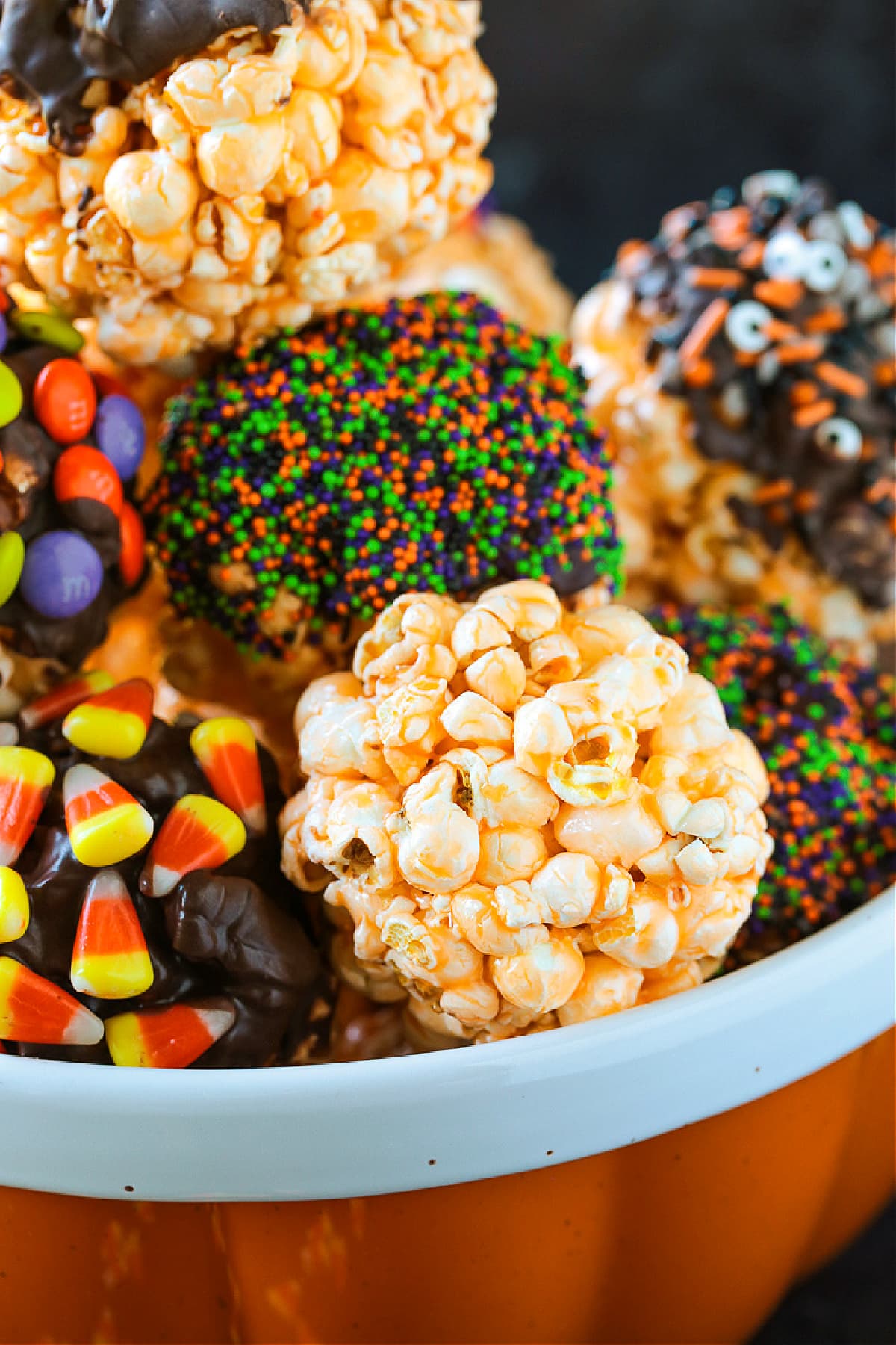 Halloween Popcorn Balls are a tasty and festive homemade treat for Halloween! Perfect for trick-or-treaters or for a Halloween party favor! popcorn balls in bowl decorated for Halloween