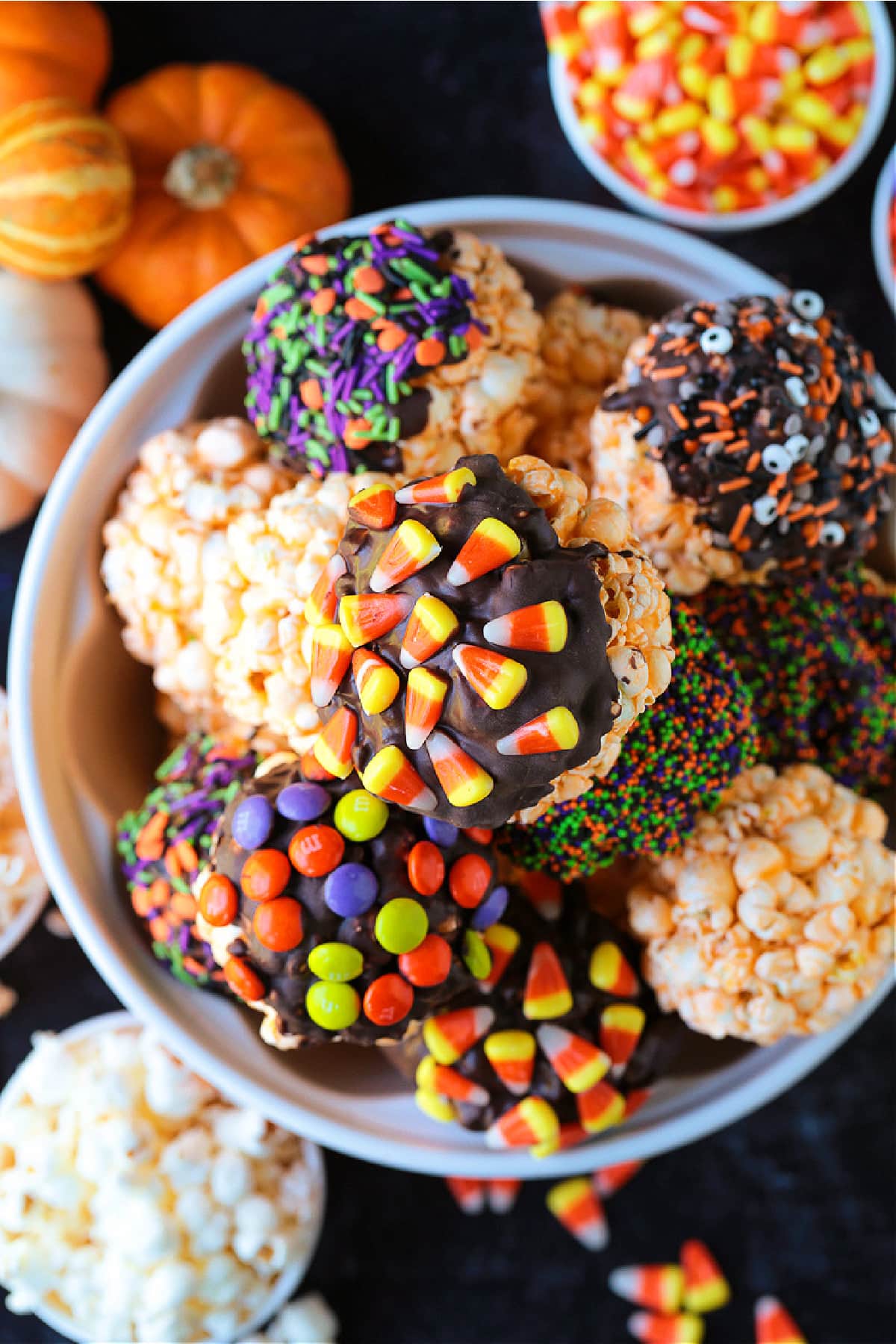 Halloween Popcorn Balls are a tasty and festive homemade treat for Halloween! Perfect for trick-or-treaters or for a Halloween party favor! decorated halloween popcorn balls in bowl