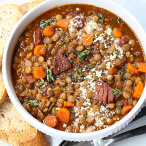 lentil soup with ham in a bowl with toast and spoon on the side