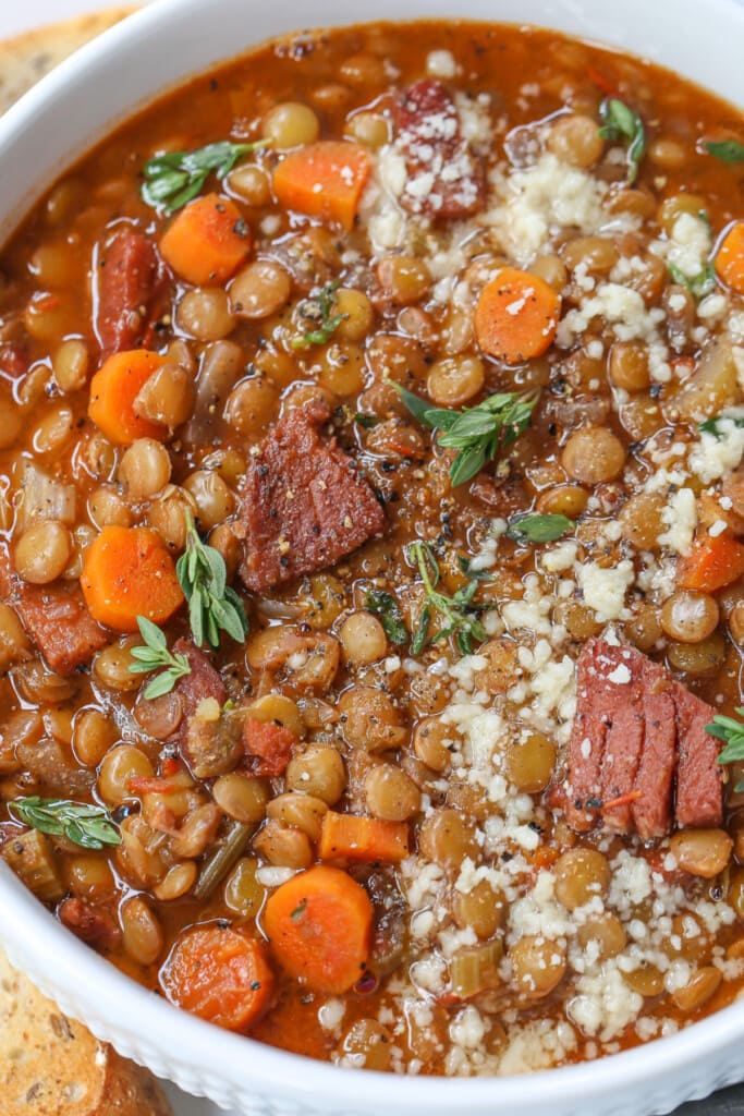 lentil soup with ham in a bowl with parmesan cheese and fresh thyme