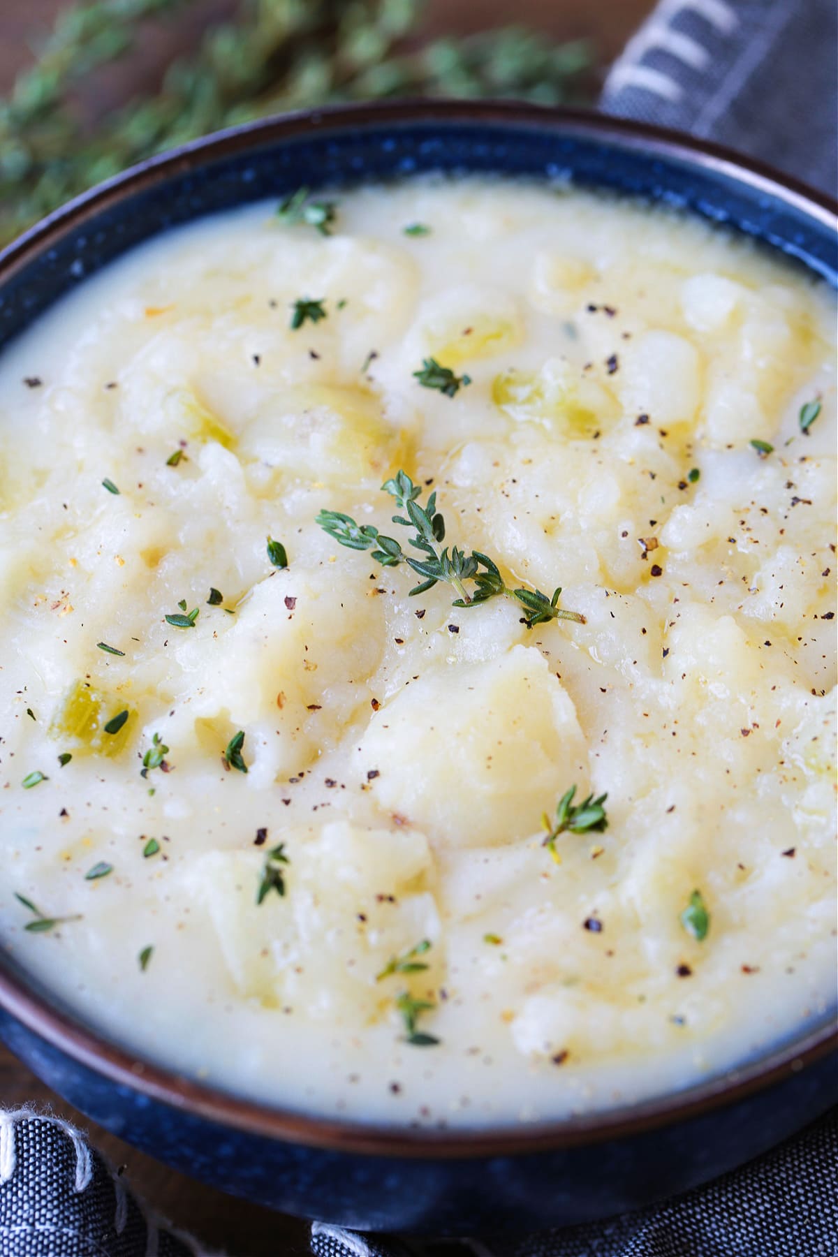 potato soup in a bowl with thyme and a napkin on the side