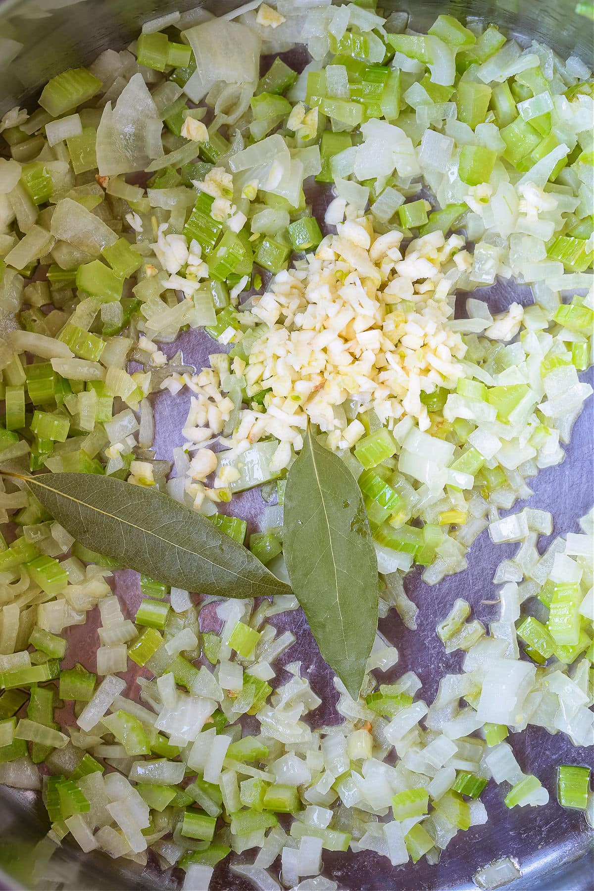 diced celery and onions in a pot with bay leaves